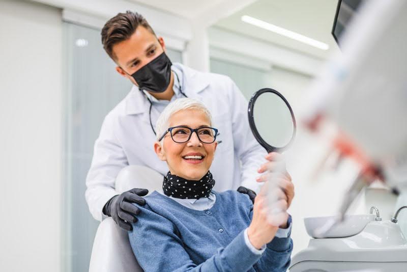 Smiling patient with Affordable Dental Implants being examined by a dentist